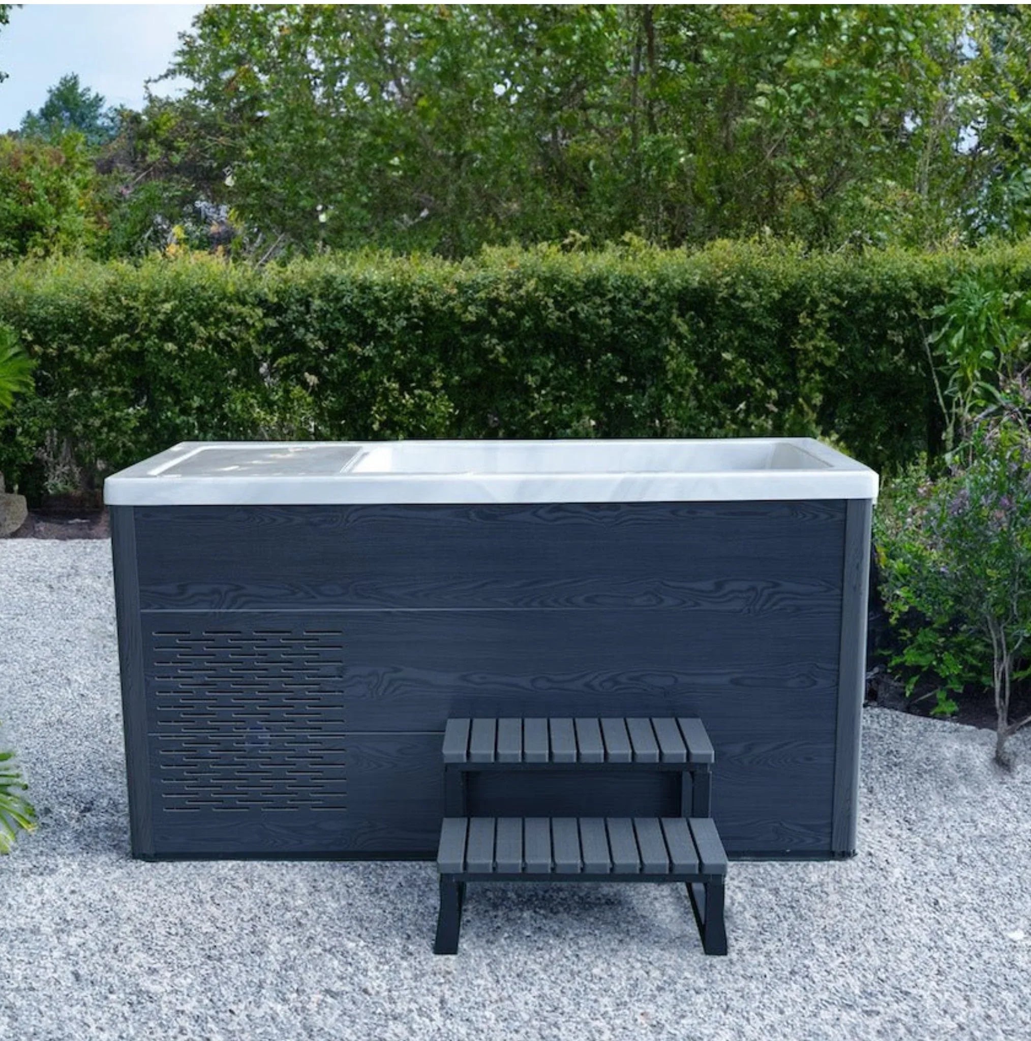 Moderner Outdoor Whirlpool in Grau mit Stufen auf Terrasse, umgeben von Garten für Wellness