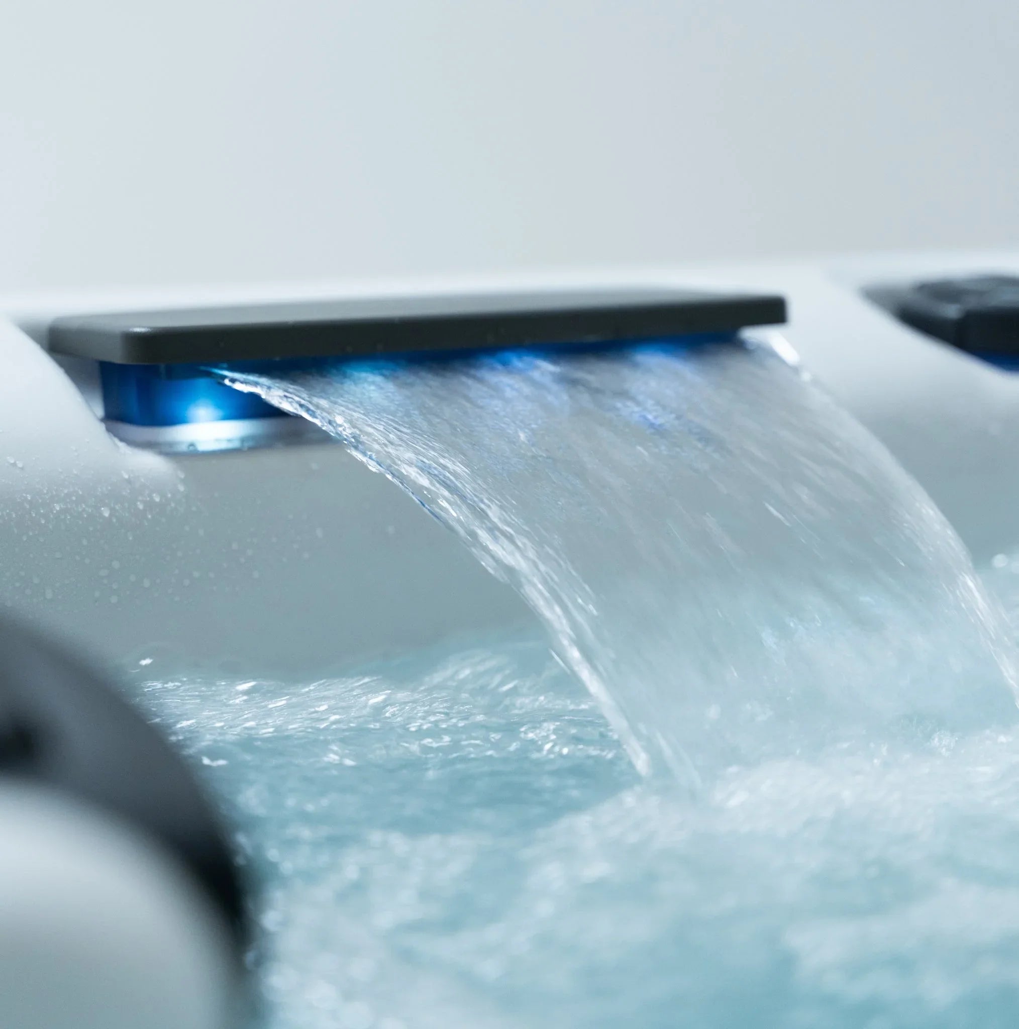 Detail eines modernen Outdoor Whirlpools mit LED-Wasserfall und sprudelndem Wasser