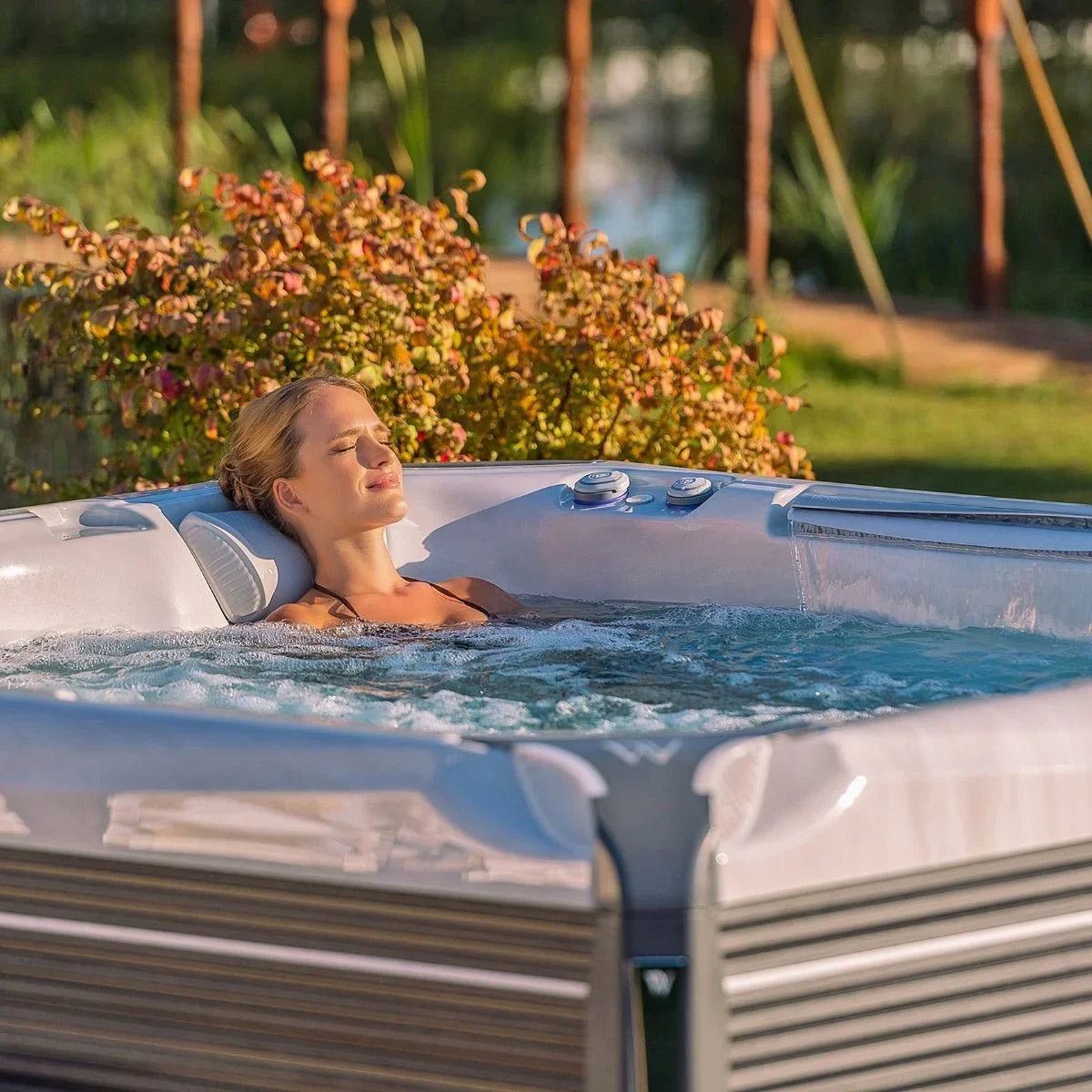 Frau entspannt im Wellis Outdoor Whirlpool auf Terrasse, luxuriöse Wellness-Atmosphäre im Garten