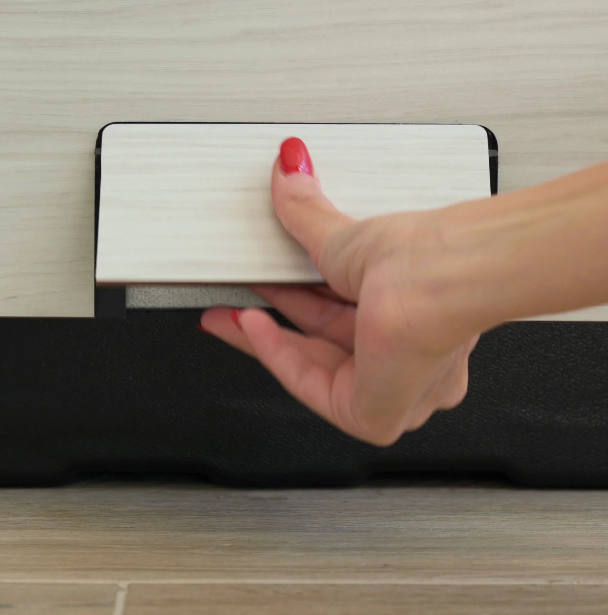 Detailaufnahme einer Hand, die ein Whirlpool-Verkleidungselement aus Holz-Optik öffnet