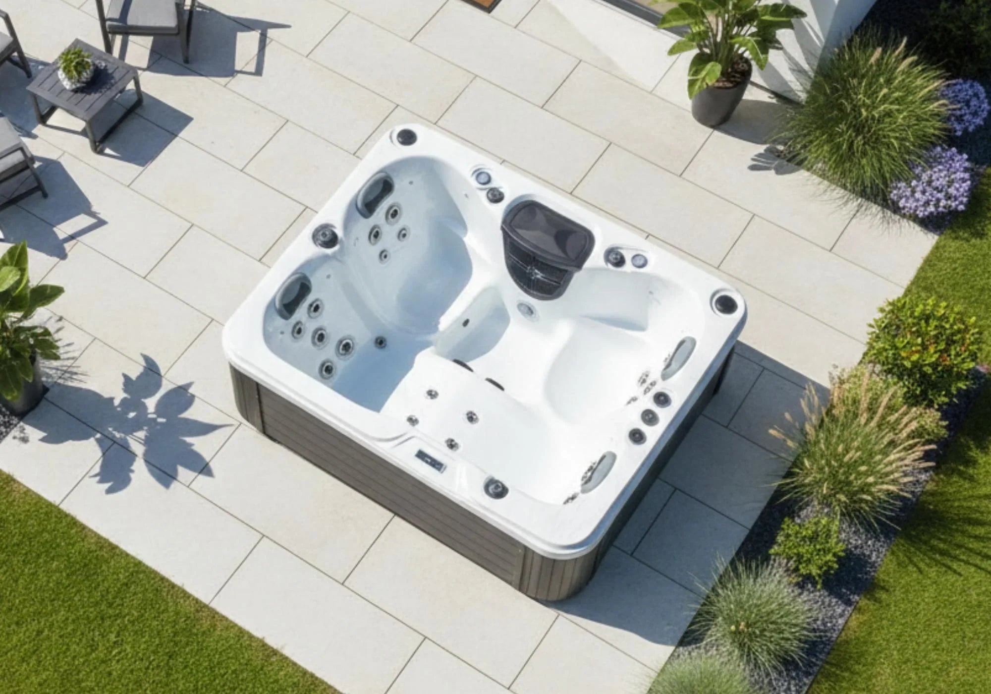 Luxuriöser Outdoor Whirlpool auf moderner Gartenterrasse, umgeben von Pflanzen und Lounge-Möbeln