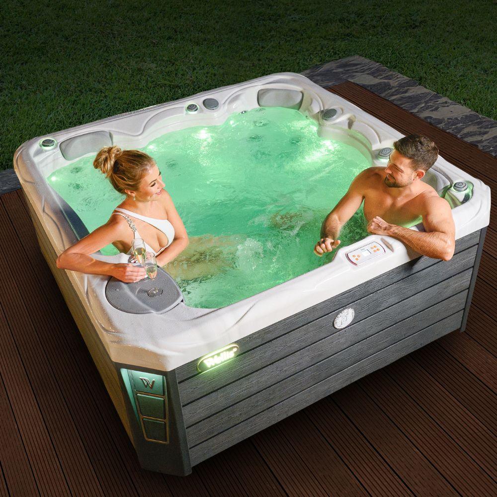 Luxuriöser Wellis Outdoor Whirlpool auf Terrasse, zwei Personen genießen Wellness-Atmosphäre im Garten