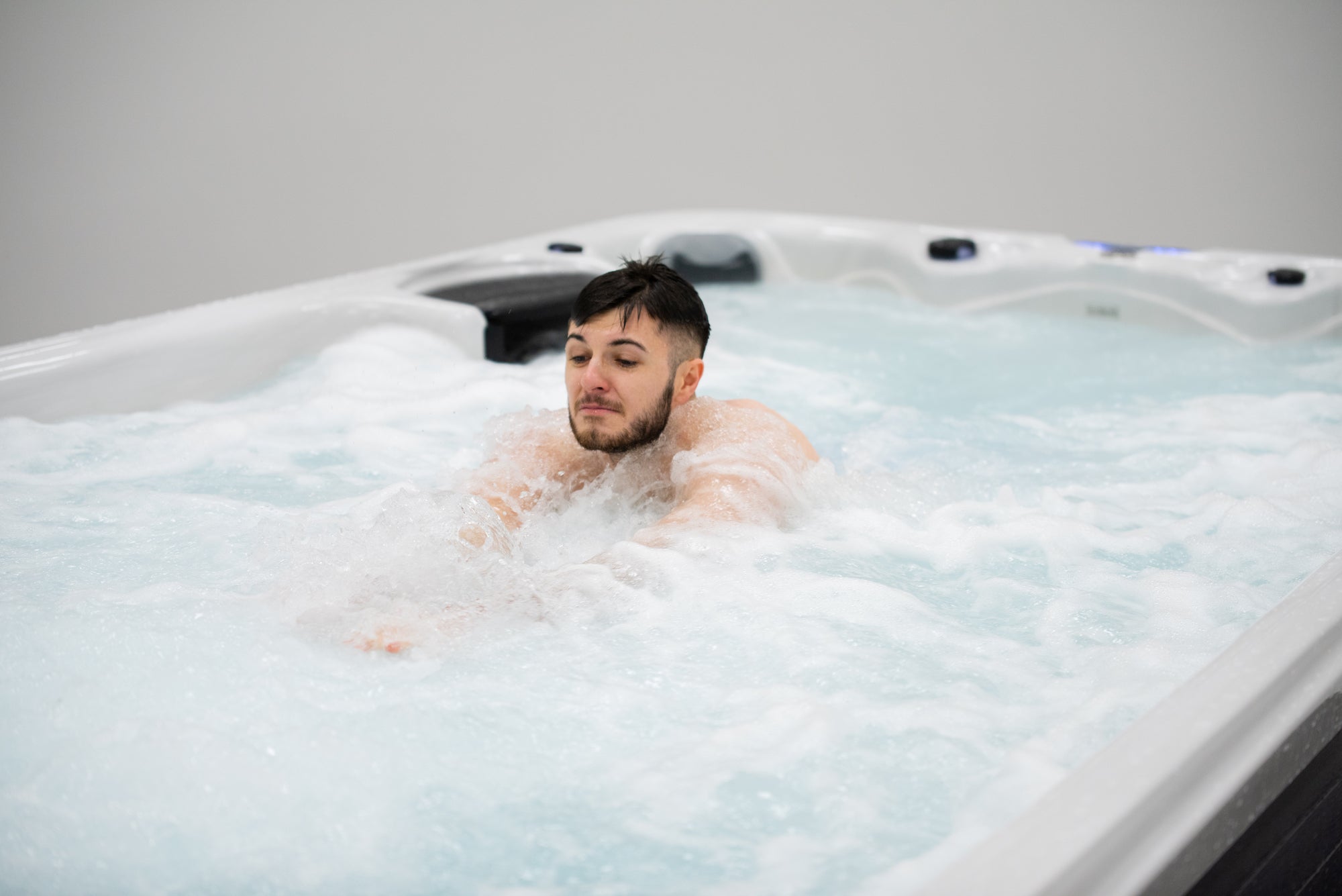 Mann entspannt im New Wave Hydro XL 430 Swim Spa mit Massagedüsen und sprudelndem Wasser für Wellness und Entspannung.